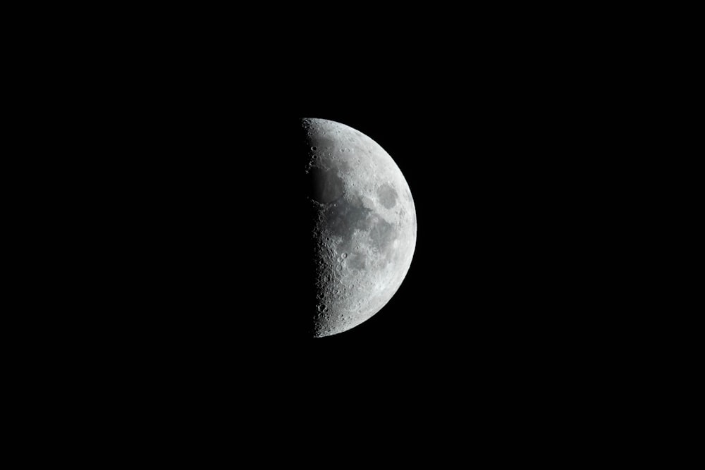 a half moon is seen in the dark sky