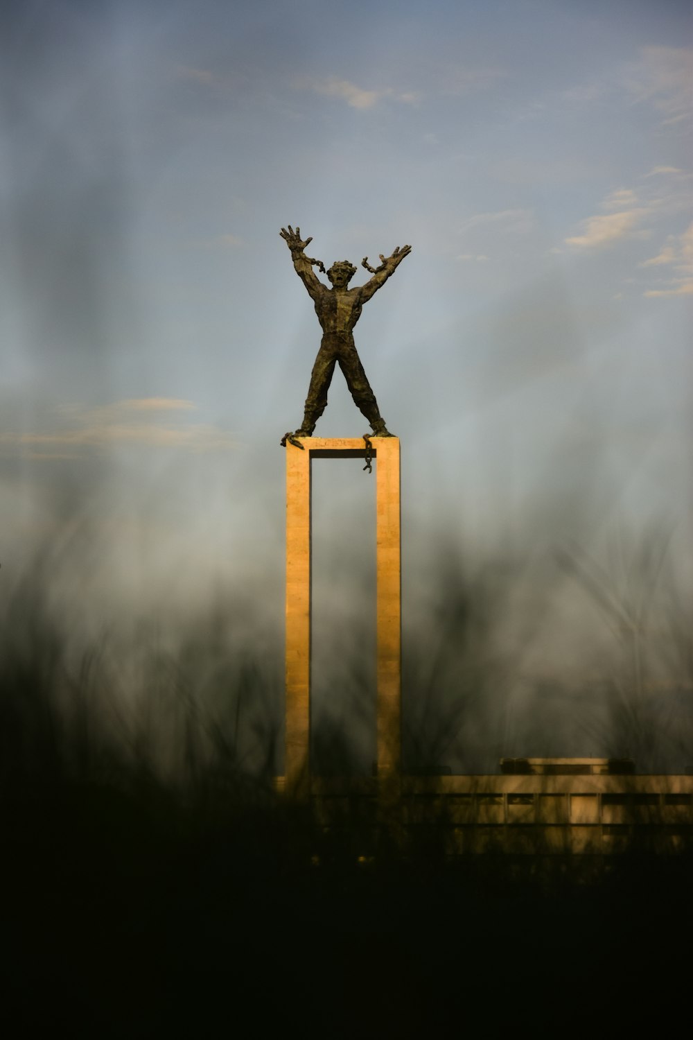a statue of a man standing on top of a wooden pole