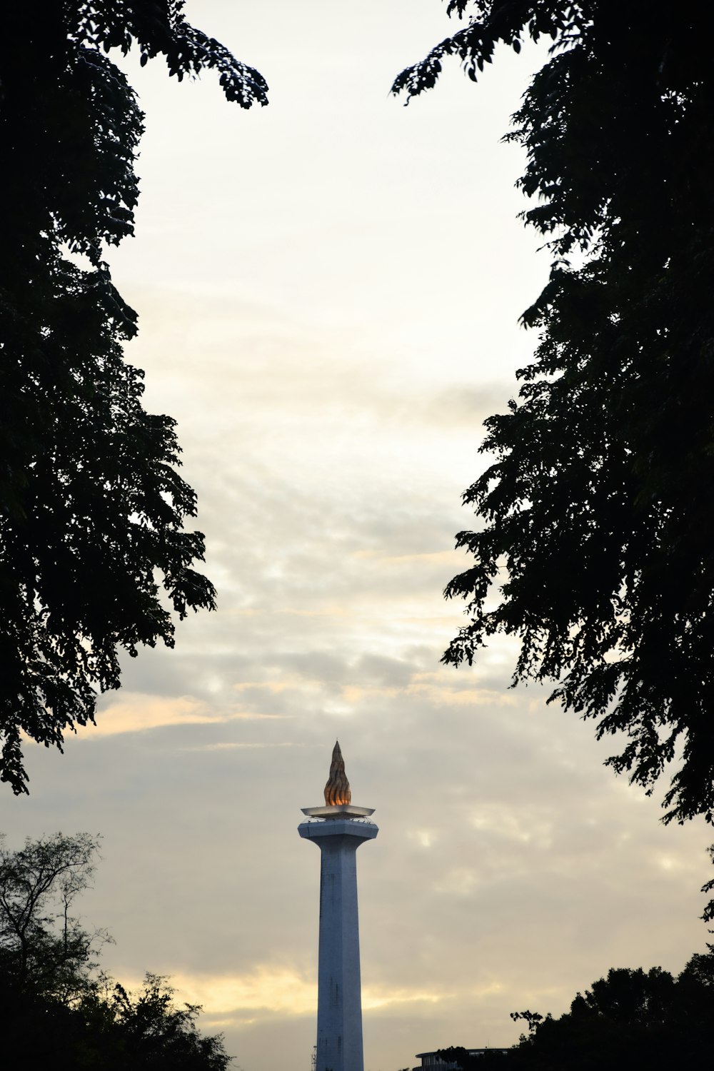 a tall white tower sitting between two trees