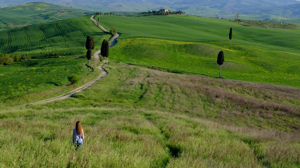 a woman walking through a lush green field