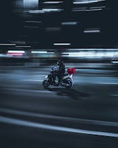 Delivery courier riding a motorbike at night with neon city lights in the background.