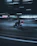 A professional courier on a red motorbike navigating through city traffic at sunset.