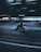 A professional courier on a red motorbike navigating through city traffic at sunset.