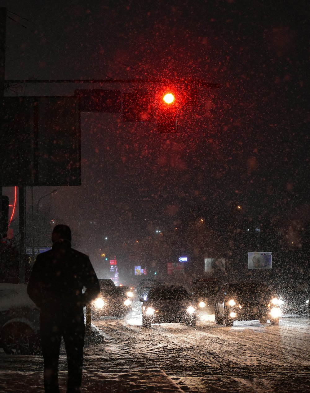 a man standing in the snow under a traffic light