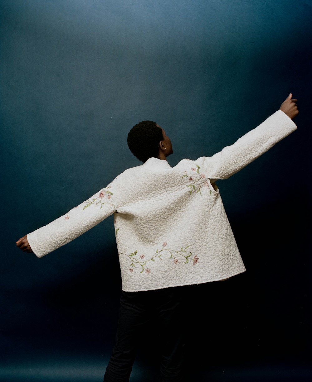 a man in a white robe standing in front of a blue background