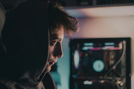 a man in a hoodie looking at a computer screen