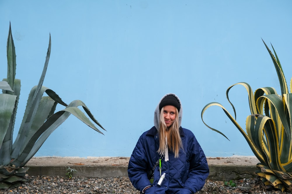 a woman sitting on the ground in front of a blue wall