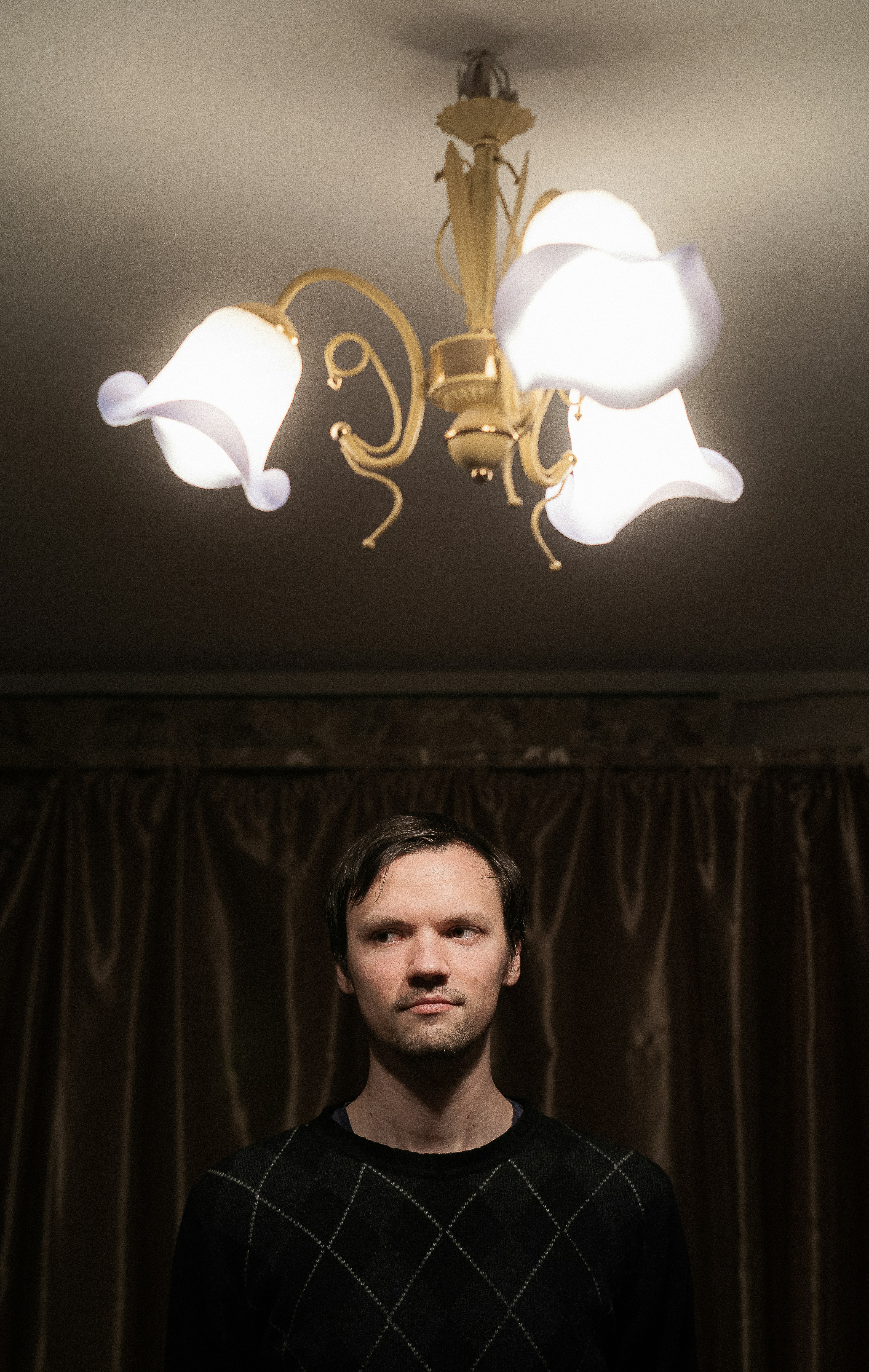 um homem em pé na frente de um lustre