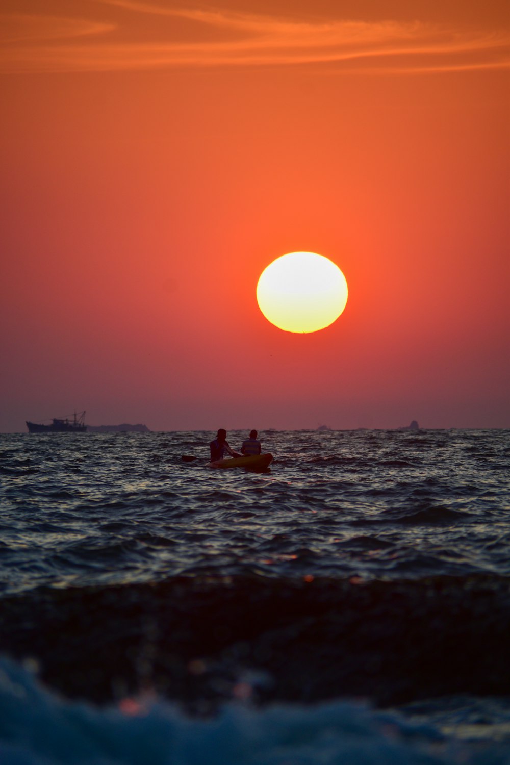 a couple of people in a small boat at sunset