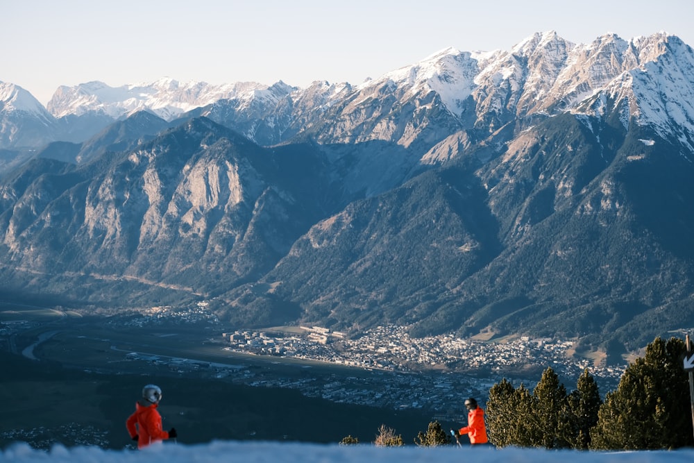 a couple of people standing on top of a snow covered slope