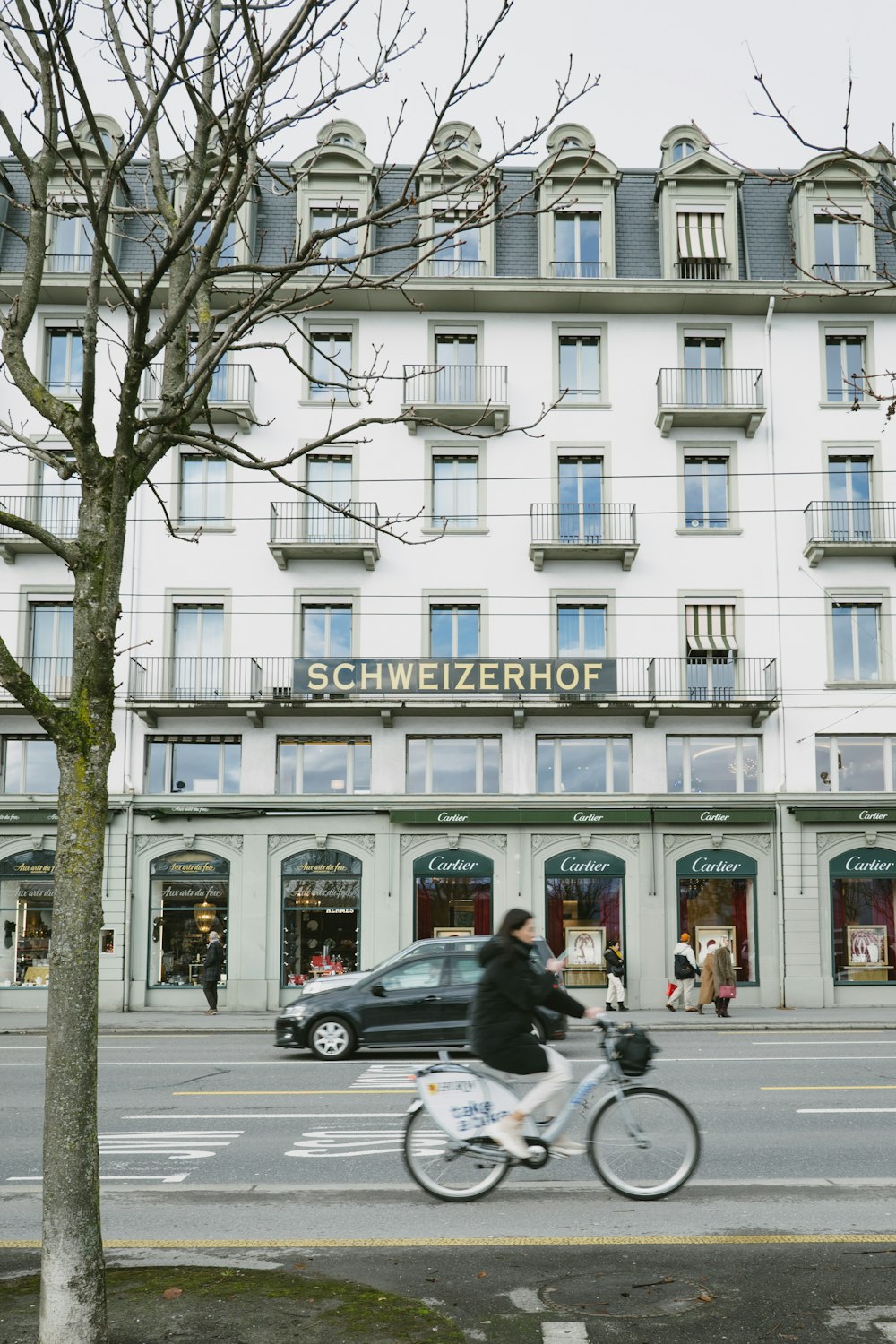 a man riding a bike past a tall white building