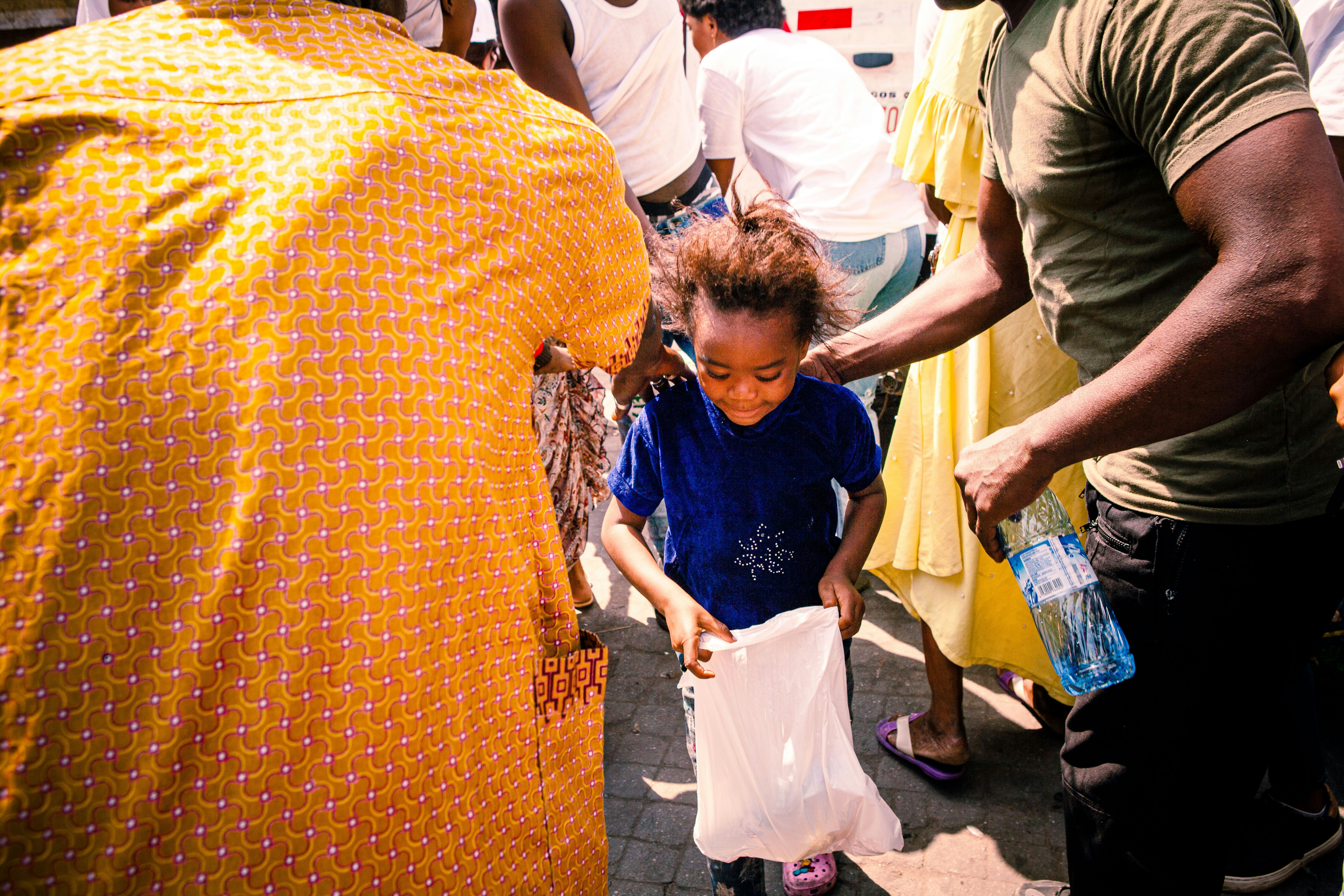 a little girl holding a white bag in her hands, Pictures from an outreach organized by WEFEED (an initiative that feeds over 1000 kids every year)