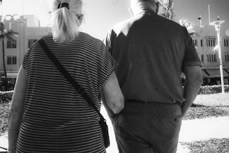 A gentle companion walking arm-in-arm with a senior outdoors during a sunny day.