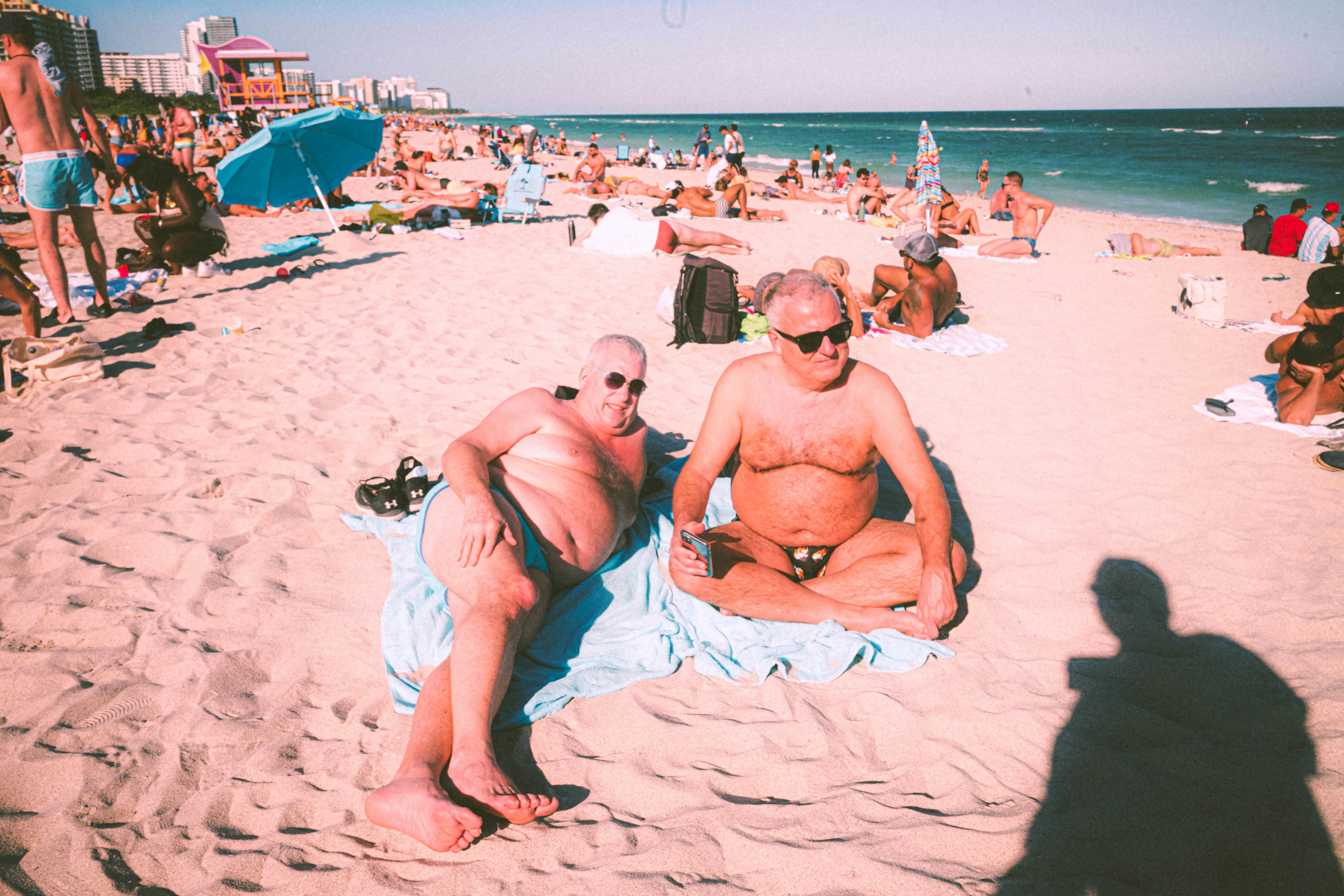 a couple of men sitting on top of a sandy beach
