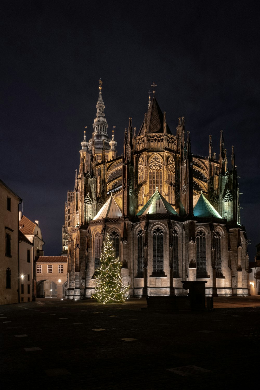 a large cathedral lit up at night with a christmas tree in front of it