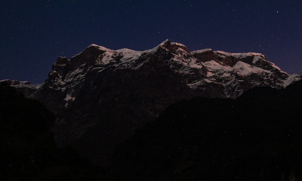 the night sky over a mountain range with stars in the sky