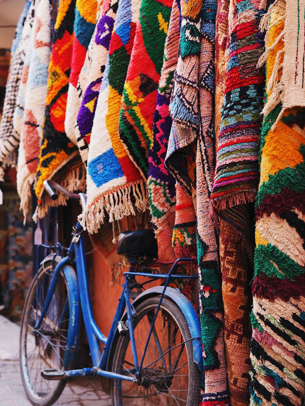 a bike parked next to a wall covered in blankets