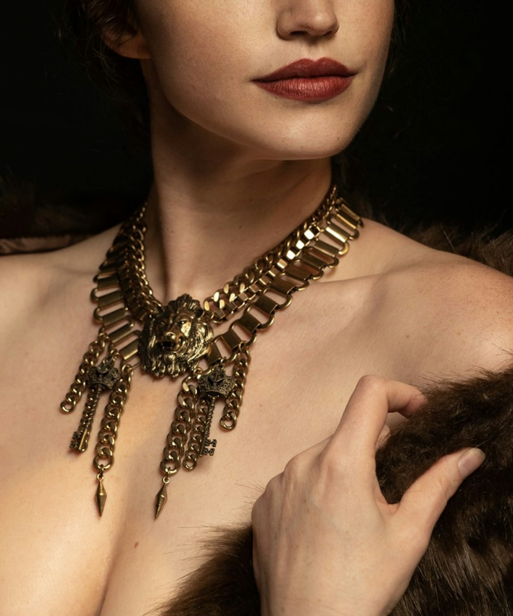 a woman wearing a gold necklace and a fur collar