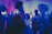 Colored lights illuminating a lively party scene with people dancing joyfully.