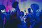 A lively wedding dance floor with happy guests dancing under colorful lights.