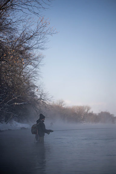 a man standing in a river holding a fishing rod