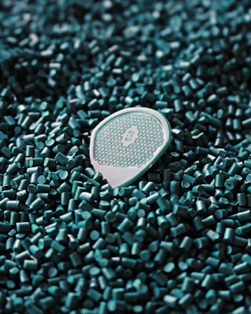 a close up of a tennis racket laying on a pile of green tiles