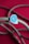 A braided rope with a zigzag pattern in shades of teal and white, accented by a plastic piece with intricate designs and the number 9.8. The background is a rich magenta, which contrasts with the color of the rope.