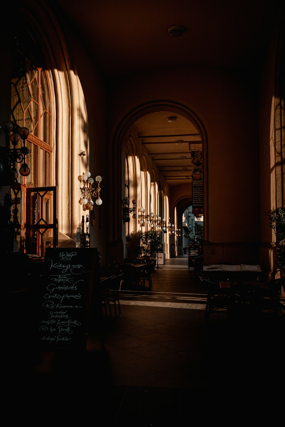 a dimly lit hallway with arched windows and tables