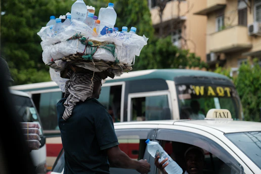 A delivery person handing over a water container to a shop owner in a bustling market.