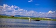 A serene riverbank scene with a fisherman patiently waiting for a bite.