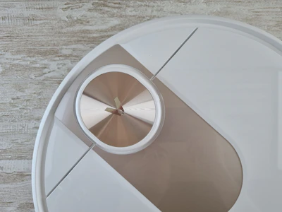 A sleek modern wall clock with a minimalist design hanging on a cozy living room wall.