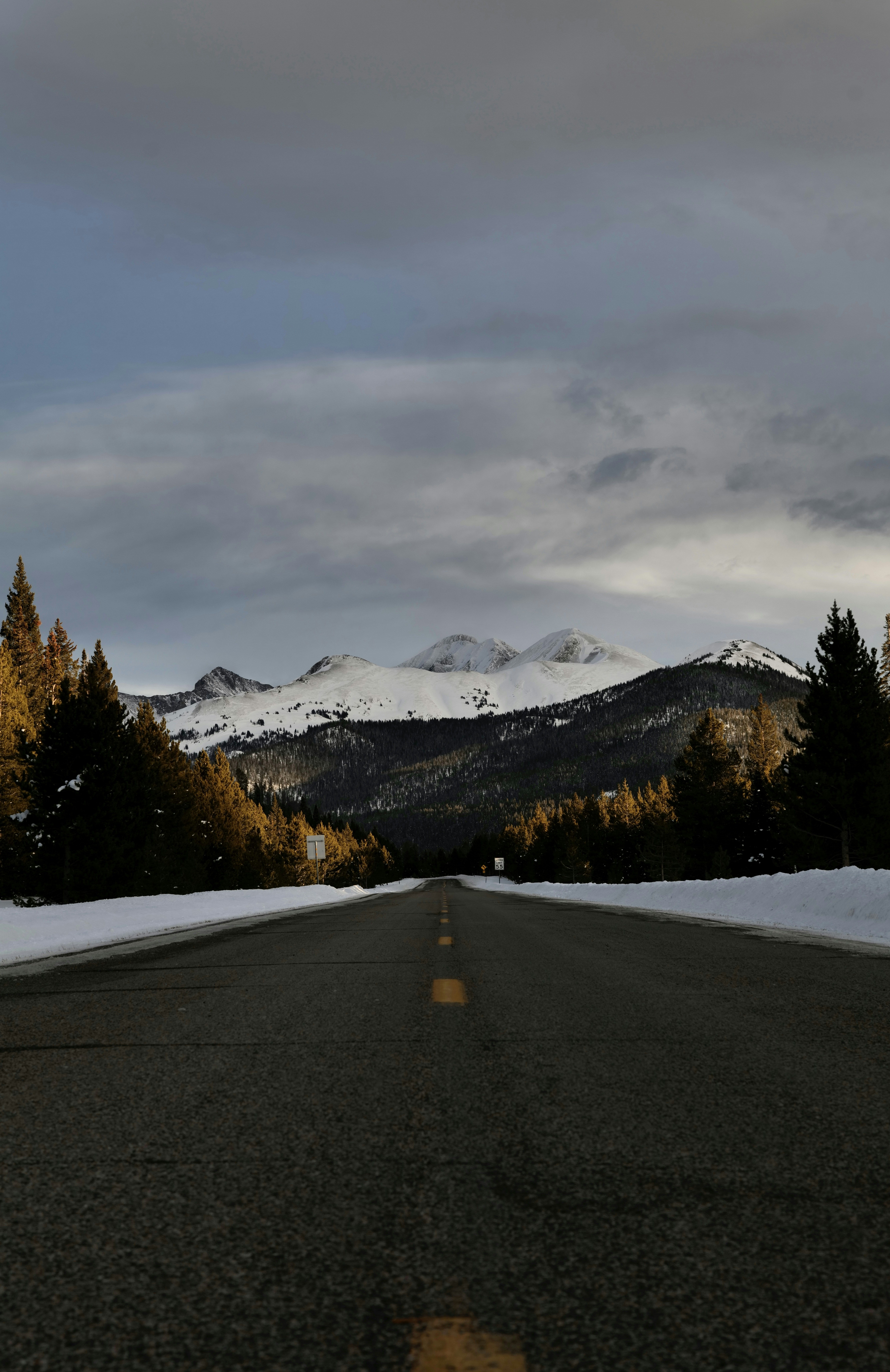 A road with snow on the ground and mountains in the background ...