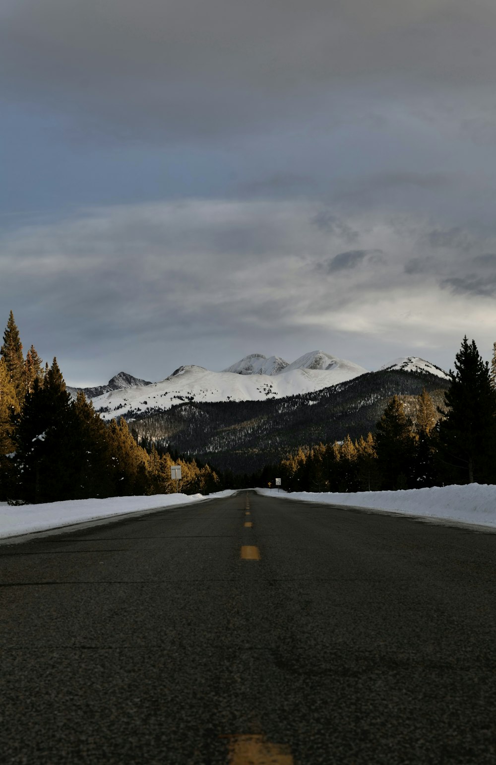 a road with snow on the ground and mountains in the background