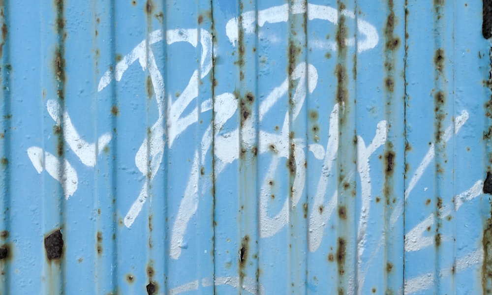 a close up of a blue metal wall with graffiti on it