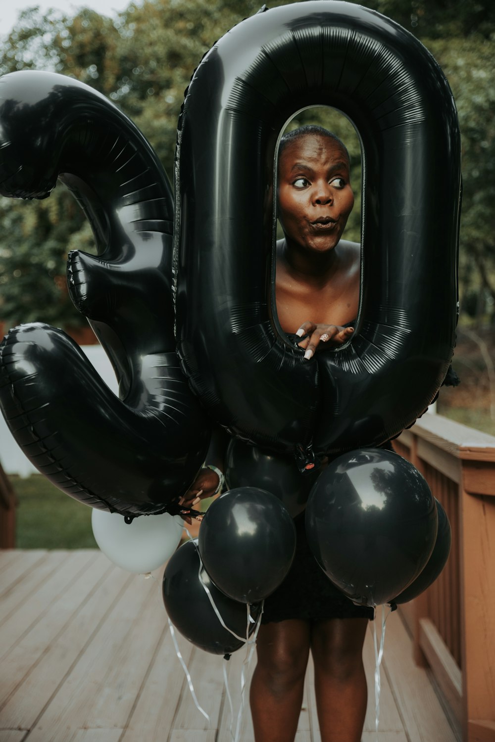 a woman holding a bunch of black balloons