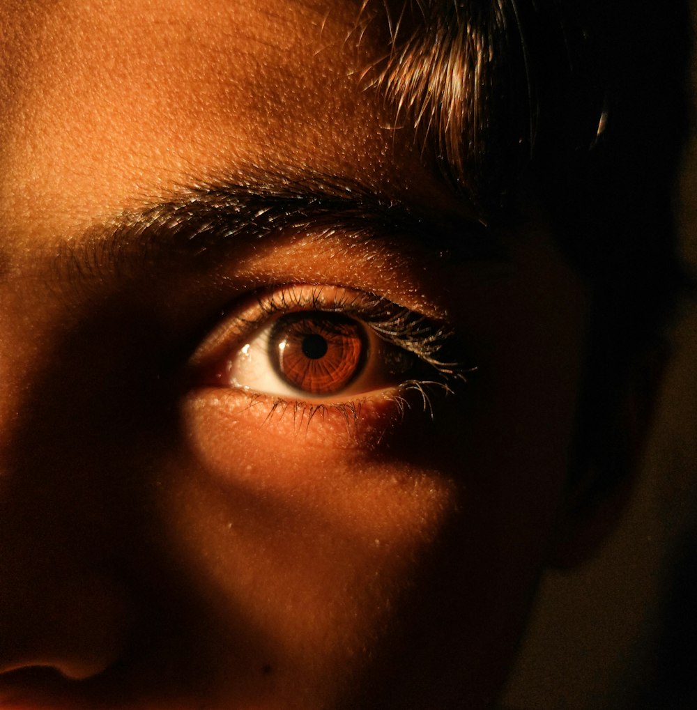 a close up of a person's face with an orange eye