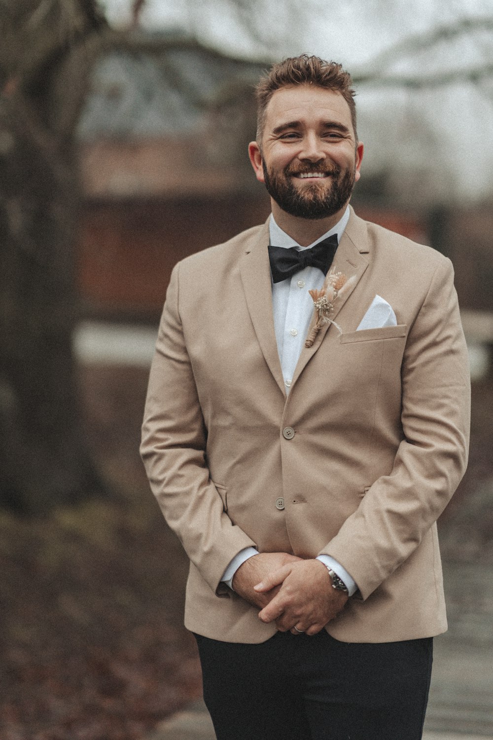 a man with a beard wearing a tan suit and bow tie