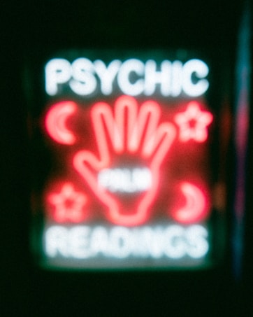 A neon sign featuring the words 'Psychic Readings' with a central image of a hand surrounded by symbols like crescent moons and stars.