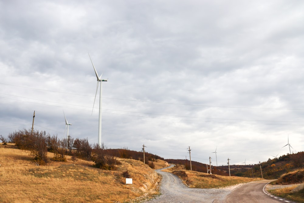 a dirt road with a wind turbine in the background