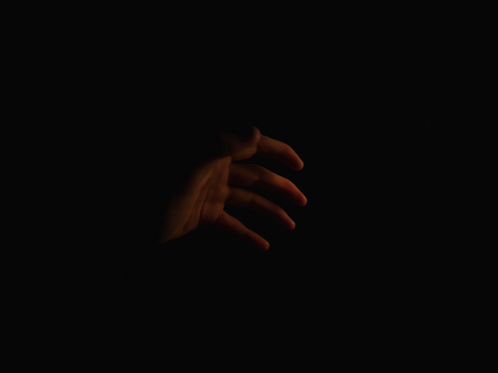 a person's hand reaching out in the dark