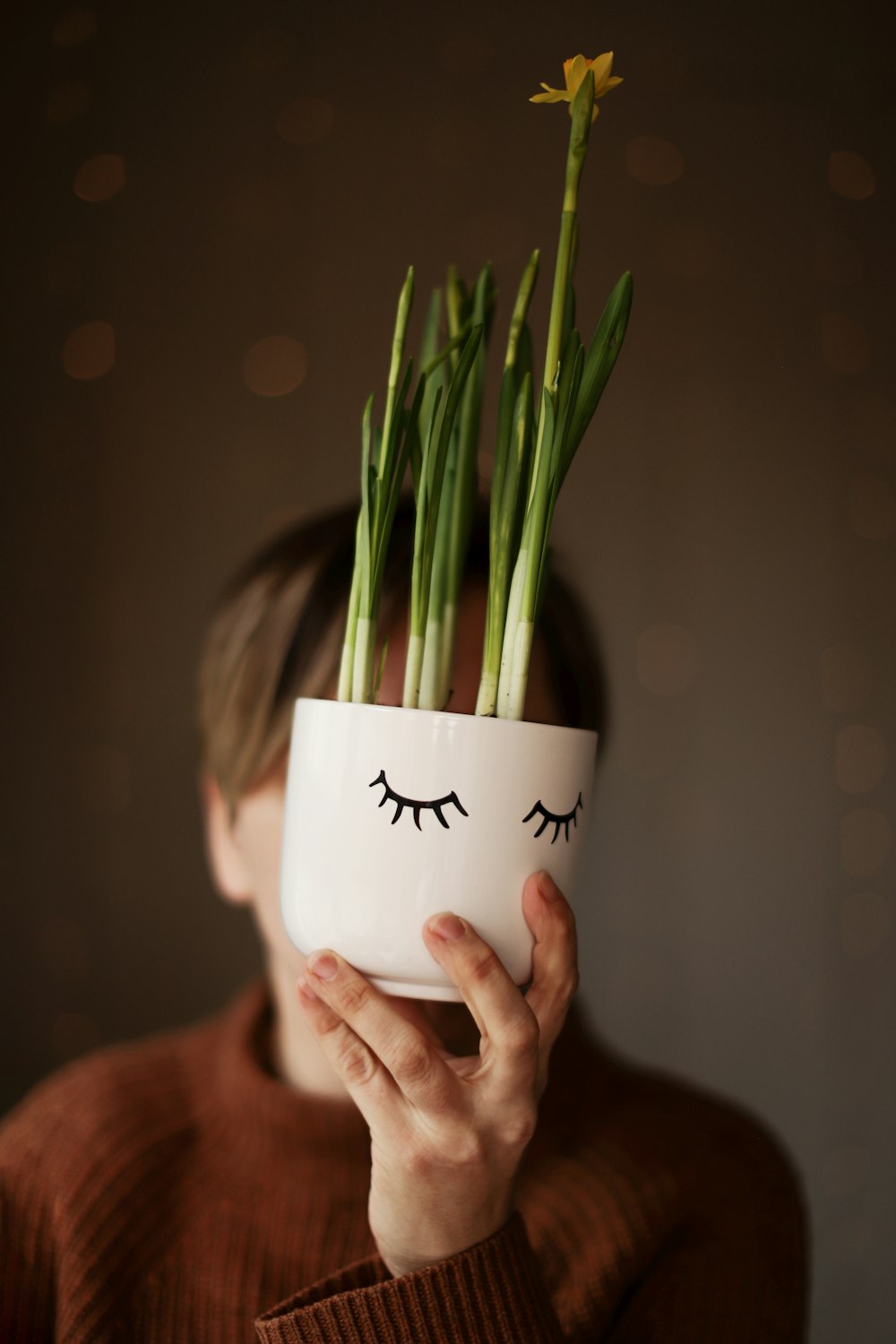 a woman holding a plant with eyelashes on it