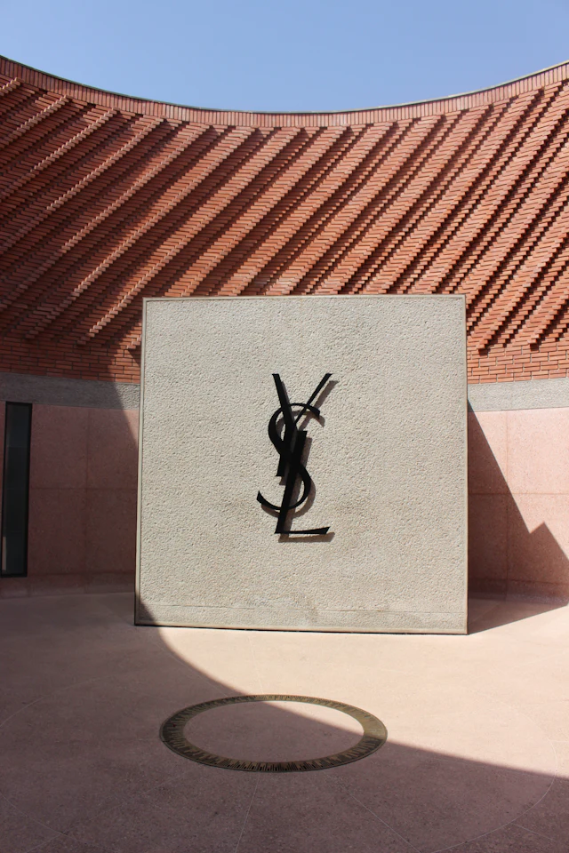 The YSL monogram sculpture against the Yves Saint Laurent Museum's curved terracotta-brick facade.