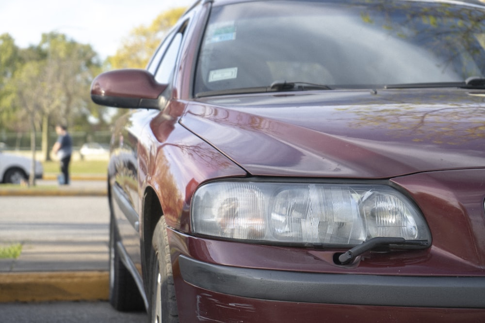 a maroon car parked on the side of the road