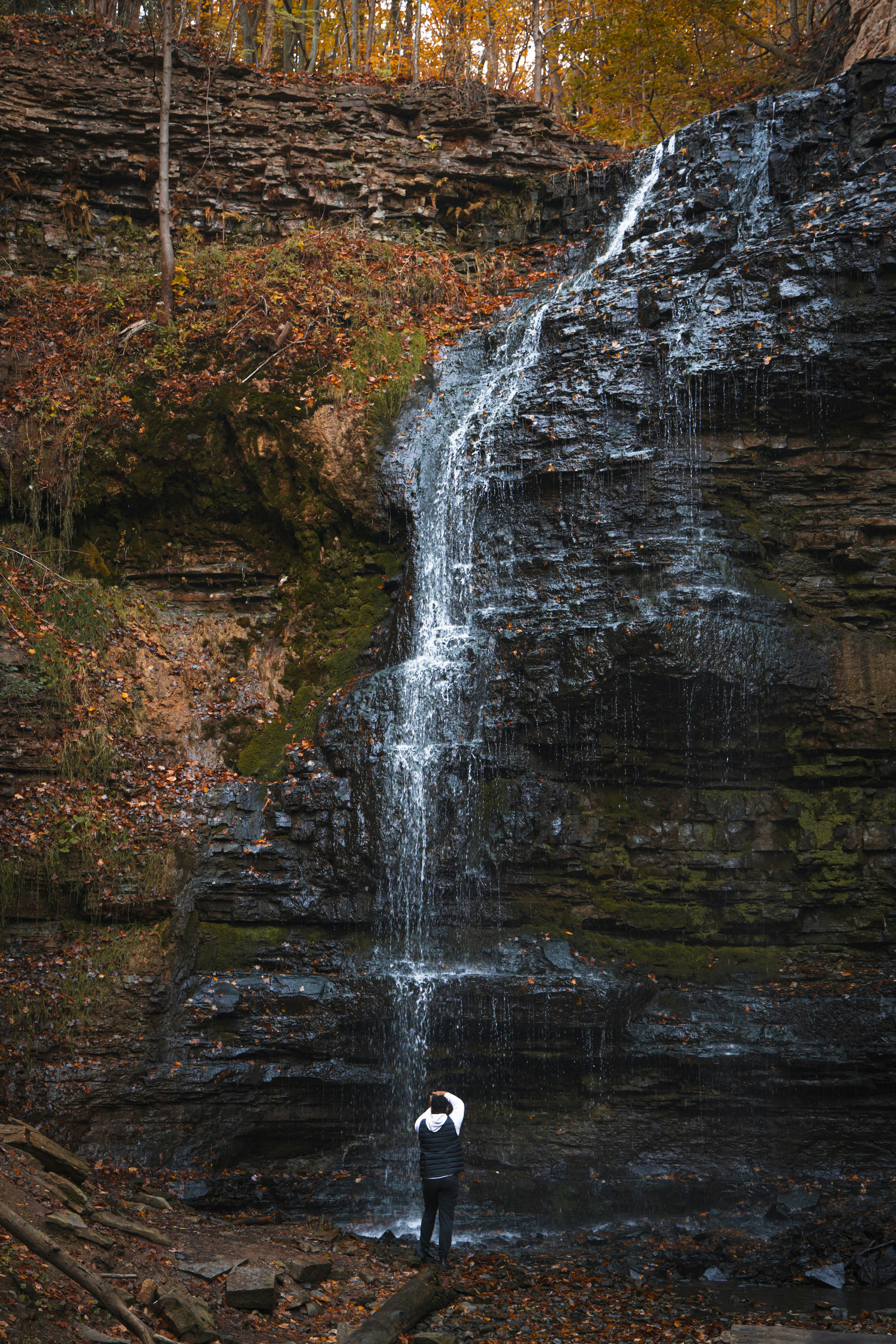 A person standing in front of a waterfall photo – Free Waterfall Image ...