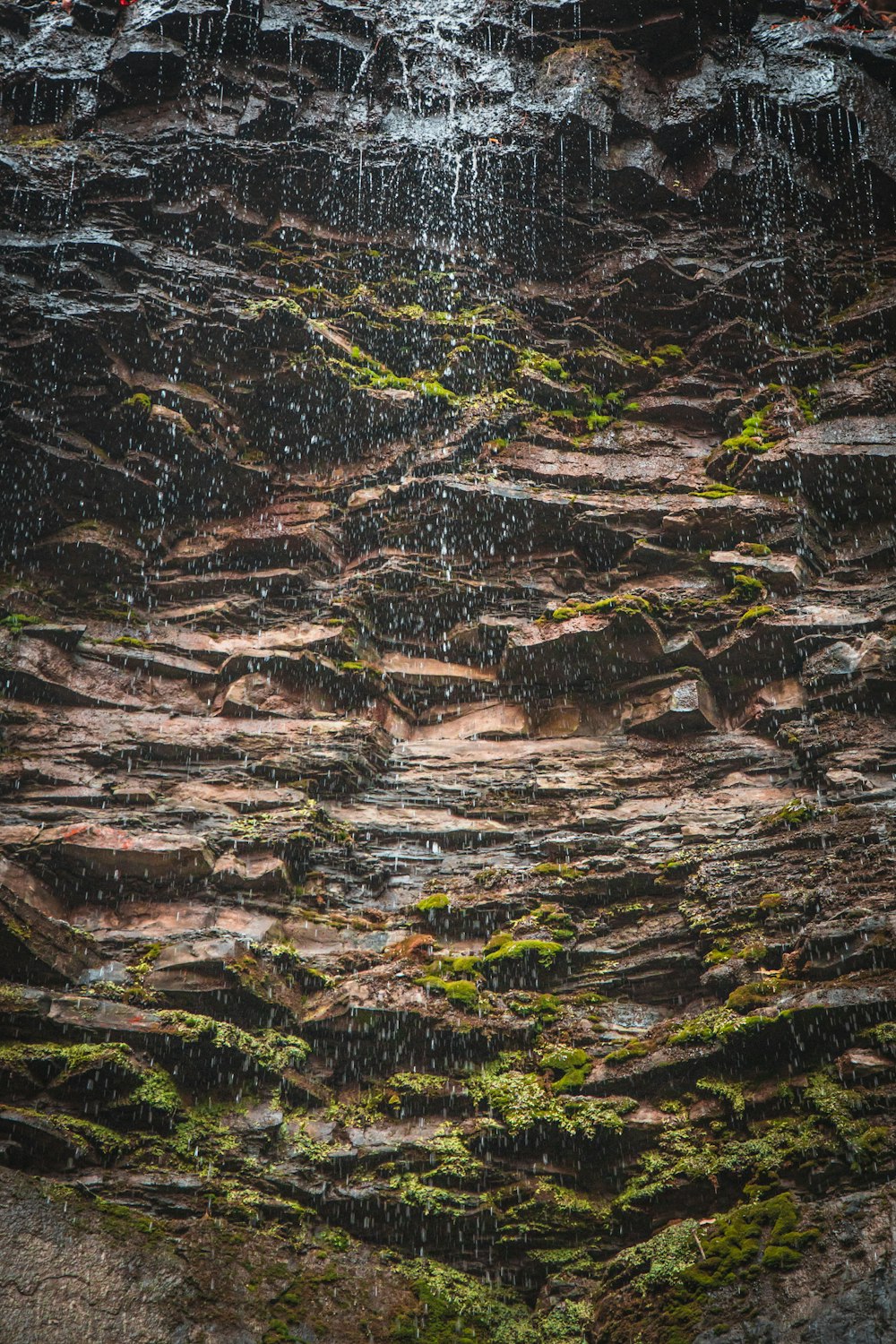 a close up of a waterfall with moss growing on it