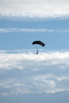 A parachutist gracefully descending against a clear blue sky.