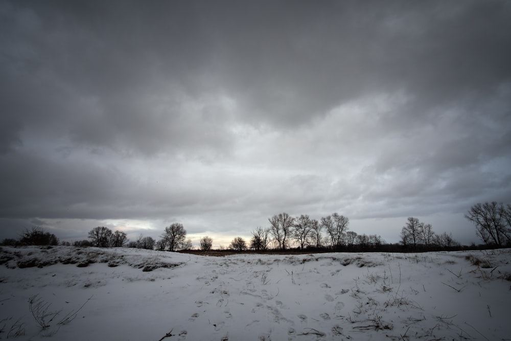 a field covered in snow under a cloudy sky