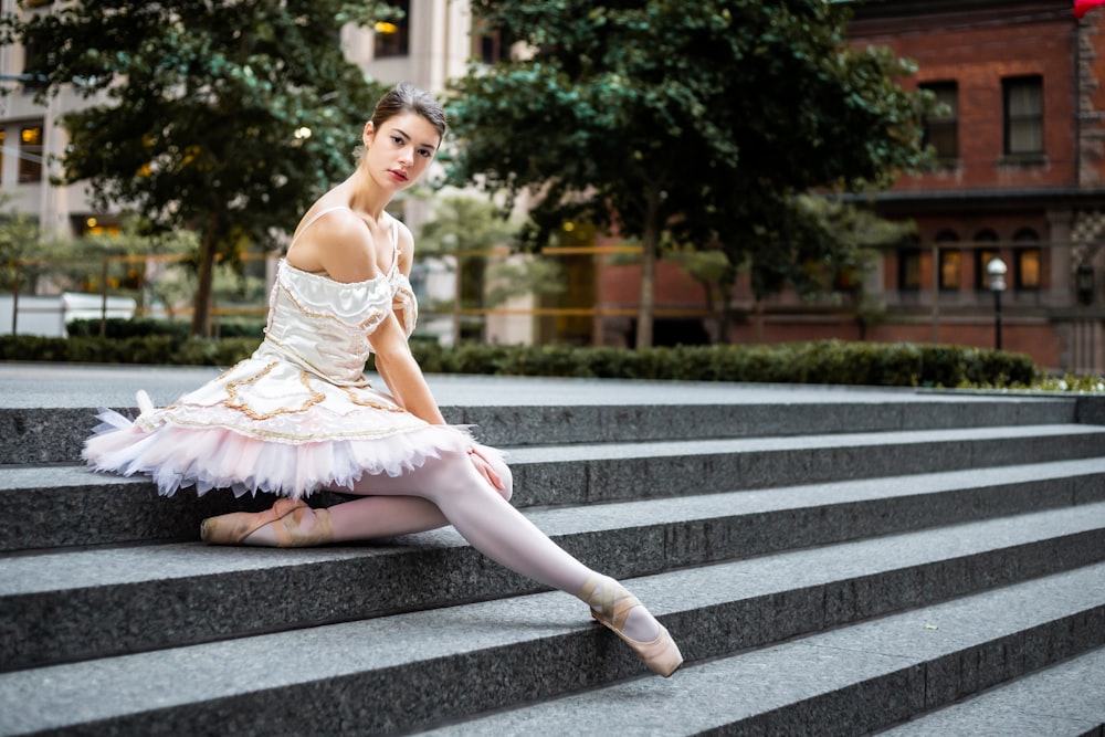 a young ballerina sitting on the steps of a building