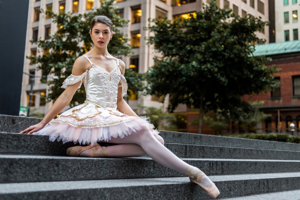 a woman in a white dress is sitting on some steps