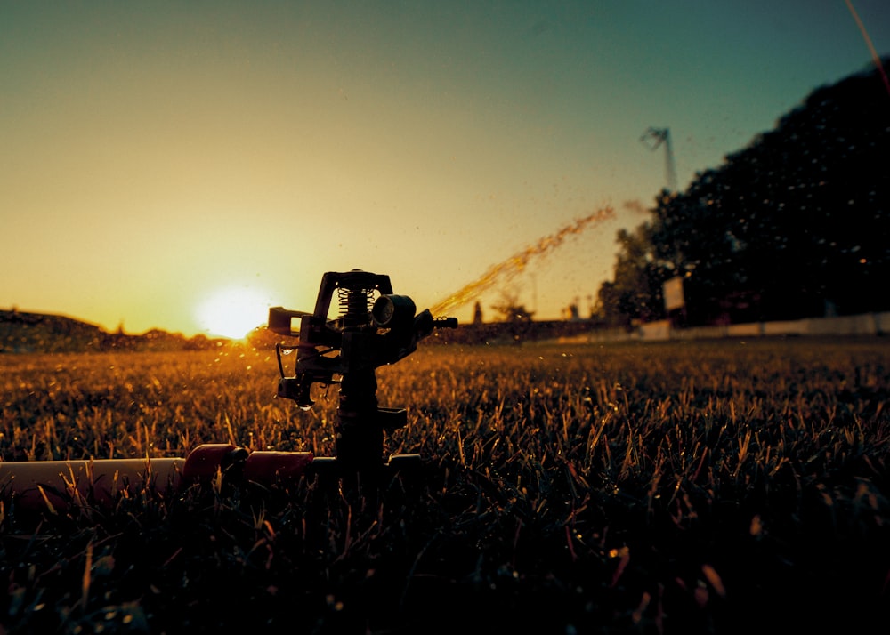 a sprinkler in the middle of a field at sunset